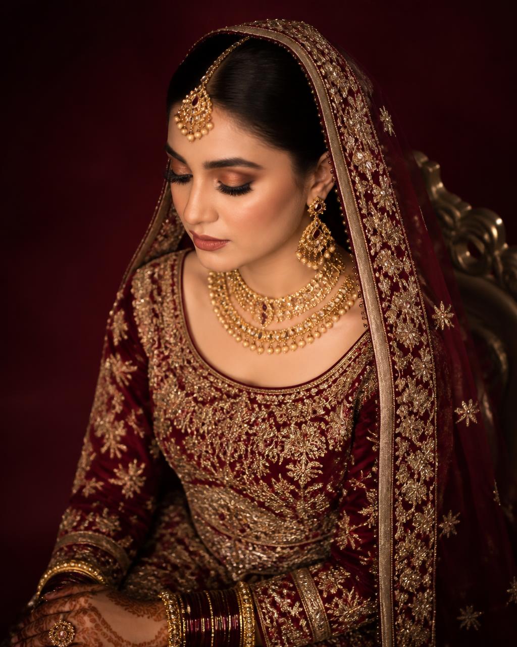 Bride in burgundy and gold bridal styling with gold jewellery
